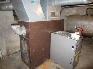 The old oil furnace (brown) sitting next to the new LP furnace (gray)